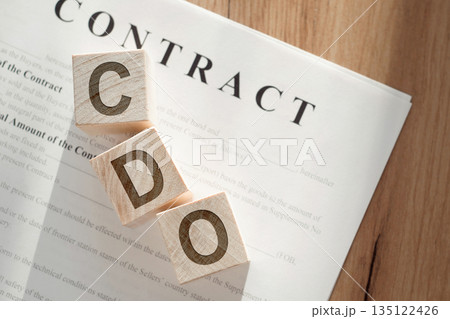 Wooden blocks spelling out CDO on a contract paper, indicating the importance of the Chief Data Officer in business. 135122426