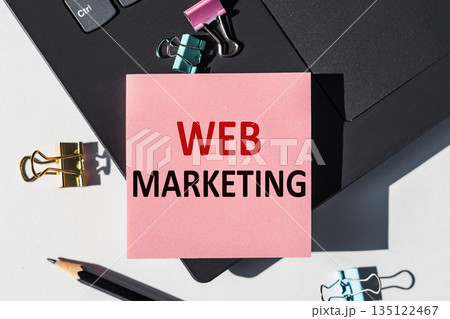 Web Marketing note is written on a paper sticker on a laptop keyboard 135122467