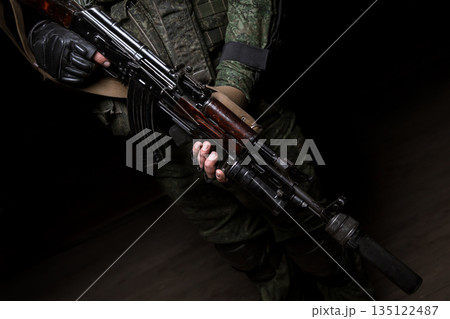 Closeup photo shoot of man's hand holding machine gun. Man is wearing military uniform and wach. Closeup photo shoot of man's hand holding machine gun. Man is wearing military uniform and wach. 135122487