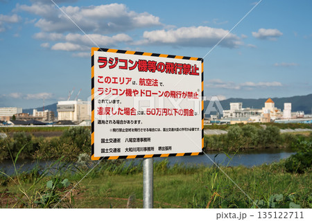 航空法に基づくドローン・ラジコン飛行禁止の警告看板と大和川の風景（八尾空港周辺・罰金明記） 135122711