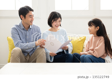 両親に通知表を見せる小学生の女の子 135122749