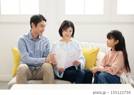 両親に通知表を見せる小学生の女の子 135122750
