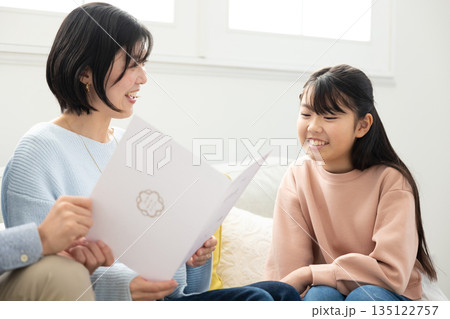 両親に通知表を見せる小学生の女の子 135122757