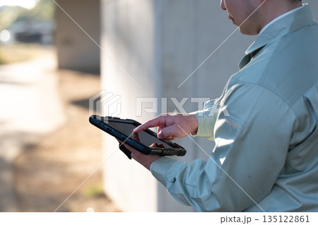 タブレット端末を操作する施工管理の男性 135122861