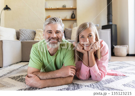 Smiling senior pair relaxing on floor Smiling senior pair relaxing on floor 135123215