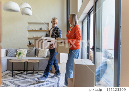 Mature couple standing with cartons during relocation Mature couple standing with cartons during relocation 135123309