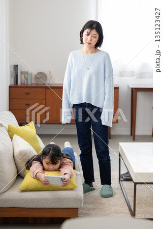 スマートフォンに夢中な娘を心配そうに見つめる母親 135123427