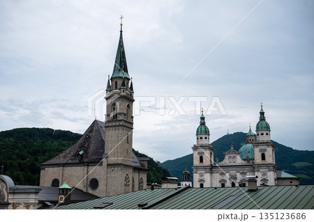 Salzburg city skyline with historic church towers and cathedral against alpine mountain backdrop 135123686
