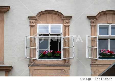 Open historic window with colorful flower boxes on classic European building facade in old town setting 135123687