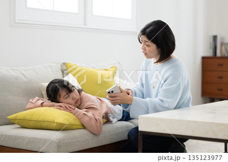 スマートフォンを手に小学生の娘を叱る母親 135123977