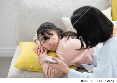 スマートフォンの使い方について叱られながら母親を睨む小学生の女の子 135123978