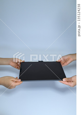 タブレットを両手で受け渡しする様子 135124238