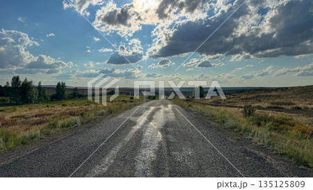 Long old road leading into the distance under a dramatic sky with sun rays breaking through clouds, symbolizing journey and endless possibilities. Long old road leading into the distance under a dramatic sky with sun rays breaking through clouds, symbolizing journey and endless possibilities. 135125809
