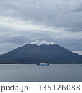 噴煙を上げる桜島と静かな錦江湾を渡るフェリー 135126088