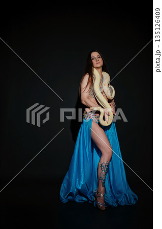 Woman performing dance with a snake in a dark studio setting at night 135126409