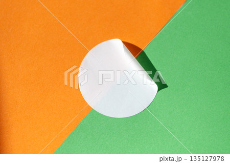 Circular white sticker on orange and green background with light shadow Circular white sticker on orange and green background with light shadow 135127978