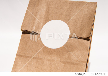 Brown paper bag with round cutout on neutral background Brown paper bag with round cutout on neutral background 135127994