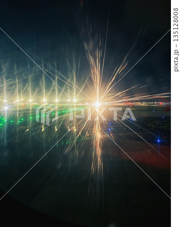 Bright runway lights, dramatic starburst effects on an airport runway at night, seen from an airplane window. Aviation, night travel, airport runway lights, aircraft movement 135128008
