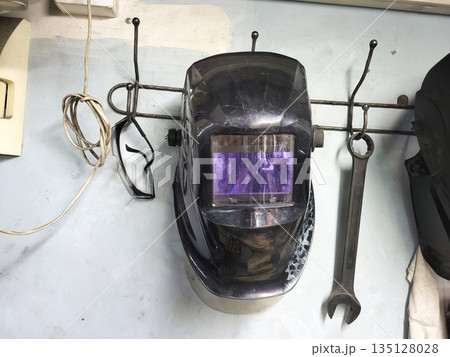 Professional welding helmet hanging on workshop wall 135128028