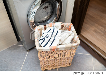 Wicker basket with laundry next to washing machine in bathroom 135128691