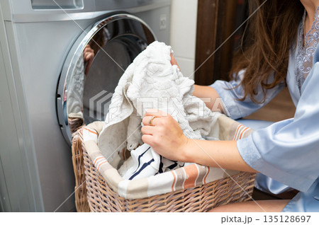 Woman taking dirty laundry from basket, close-up, preparing to do laundry 135128697