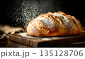 Rustic loaf of freshly baked bread sprinkled with flour on wooden board 135128706