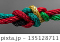 Colorful intertwined synthetic ropes tied in a complex knot on gray background 135128711