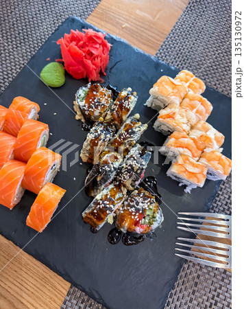 Sushi roll set served on a stone plate with wasabi and pickled ginger, Japanese cuisine presentation Sushi roll set served on a stone plate with wasabi and pickled ginger, Japanese cuisine presentation 135130972