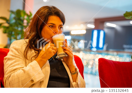 Woman enjoying coffee while sitting in cafe during shopping break. Everyday leisure moment, relaxation pause and modern urban lifestyle in real life commercial environment Woman enjoying coffee while sitting in cafe during shopping break. Everyday leisure moment, relaxation pause and modern urban lifestyle in real life commercial environment 135132645