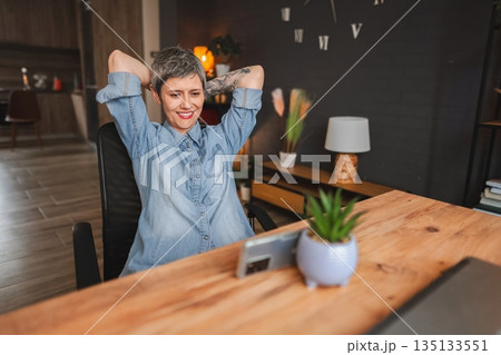 Freelancer relaxing after finishing work on a laptop at home office Freelancer relaxing after finishing work on a laptop at home office 135133551