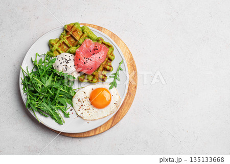 Healthy breakfast with green spinach waffles, salmon, cream cheese, fried egg and salad Healthy breakfast with green spinach waffles, salmon, cream cheese, fried egg and salad 135133668