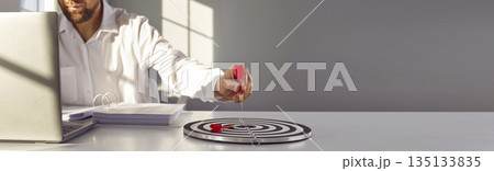 Man with target board and dart arrow sets business goal on copy space banner background 135133835
