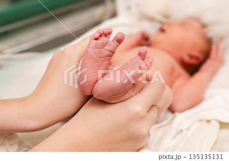 Close-up of newborn baby feet held by a parent in a hospital setting, symbolizing care, tenderness and the first moments of life 135135131