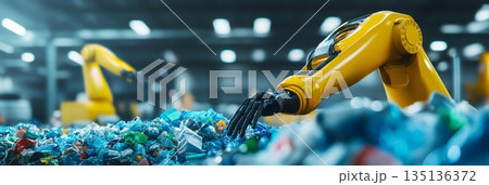 In a modern recycling facility, a robotic arm efficiently sorts through a large pile of plastic waste, contributing to environmental sustainability and automated waste management 135136372