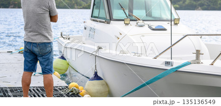 桟橋に立つ男性とボート 【撮影協力：隠岐シーサイドリゾートみやび様】 135136549