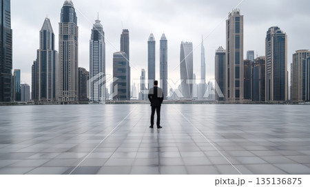 Businessman standing with hands in pockets, contemplating the dubai marina's futuristic skyline under a blanket of clouds, reflecting on ambition and future opportunities 135136875
