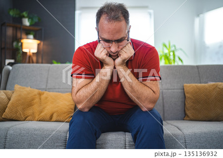 Man sitting alone at home looking sad and distraught 135136932