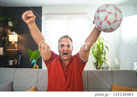 Excited middle aged man watching soccer game at home Excited middle aged man watching soccer game at home 135136965