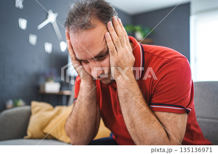 Man sitting alone at home looking sad and distraught 135136971
