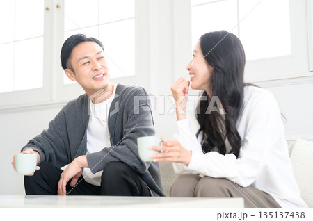 リビングでソファに座って会話をする男女 リビングでソファに座って会話をする男女 135137438