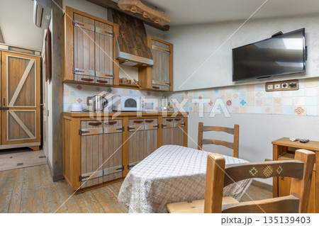 Rustic kitchen interior with wooden cabinets and dining area 135139403