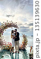 Romantic couple kissing under floral wedding arch by the sea 135139630
