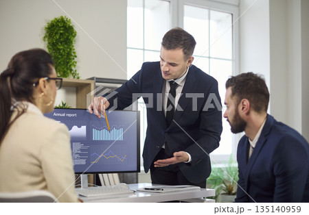 Manager presenting data insights on monitor to team during business briefing 135140959