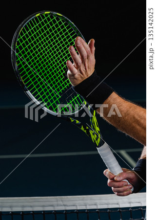 Tennis racket and hand touching strings near net 135142025