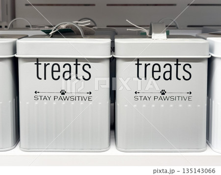 Metal containers labeled for pet treats on a shelf. 135143066