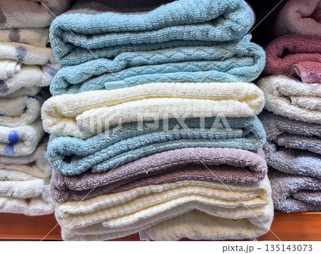 Stack of folded towels in soft pastel colors on a shelf. Stack of folded towels in soft pastel colors on a shelf. 135143073