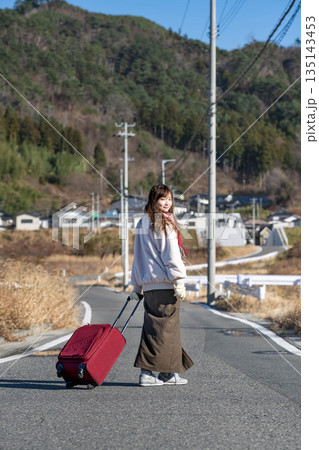 キャリーケースを引っ張る若い女性 135143453