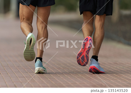 Two men running on the sidewalk, training for a marathon Two men running on the sidewalk, training for a marathon 135143520