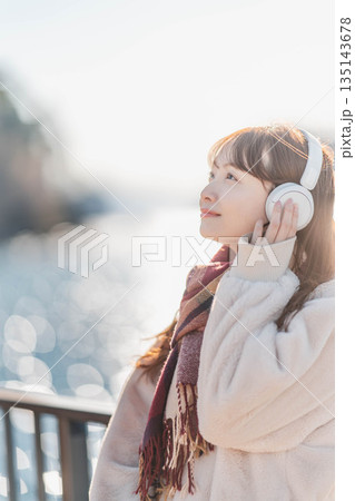 海辺に立ちヘッドホンで音楽を聴く若い女性 海辺に立ちヘッドホンで音楽を聴く若い女性 135143678