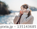 海辺に立ちヘッドホンで音楽を聴く若い女性 135143685
